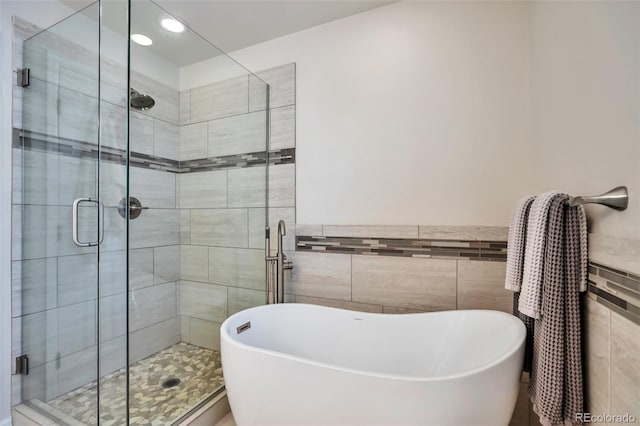 7472 S Memphis St, Aurora, CO 80016 - bathroom with tile walls, a freestanding bath, a stall shower, a wainscoted wall, and recessed lighting
