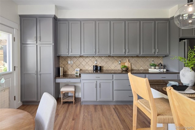 10109 E 28th Ave, Denver, CO 80238 - kitchen featuring gray cabinetry, light wood-style flooring, decorative backsplash, and dark stone countertops