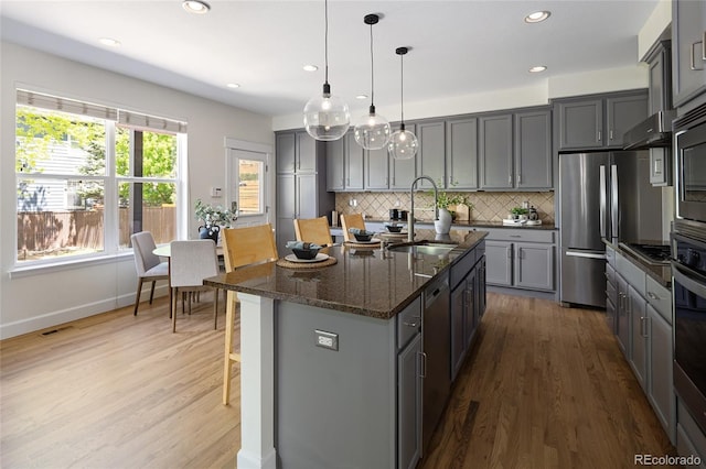 10109 E 28th Ave, Denver, CO 80238 - kitchen featuring a sink, gray cabinetry, stainless steel appliances, a breakfast bar area, and wood finished floors