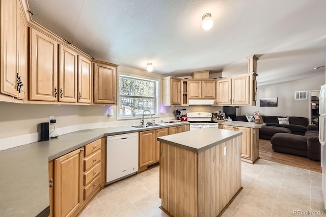 kitchen with light brown cabinetry, a sink, white appliances, and a kitchen island