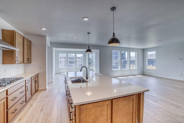 23738 E 42nd Ave, Aurora, CO 80019 - kitchen with stainless steel gas cooktop, light wood finished floors, tasteful backsplash, light stone countertops, and an island with sink