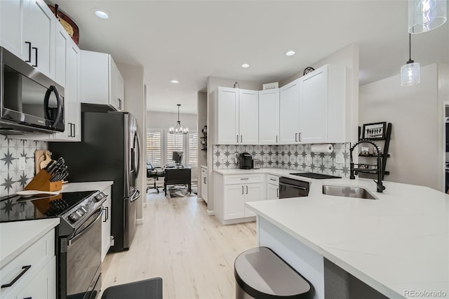 kitchen featuring stainless steel appliances, sink, light hardwood / wood-style flooring, white cabinets, and hanging light fixtures