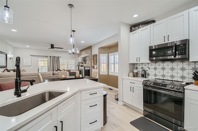 kitchen featuring sink, white cabinetry, range with electric cooktop, and hanging light fixtures