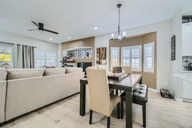 dining space featuring ceiling fan with notable chandelier and light wood-type flooring