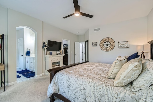 bedroom with a spacious closet, ceiling fan, ensuite bathroom, light carpet, and a closet