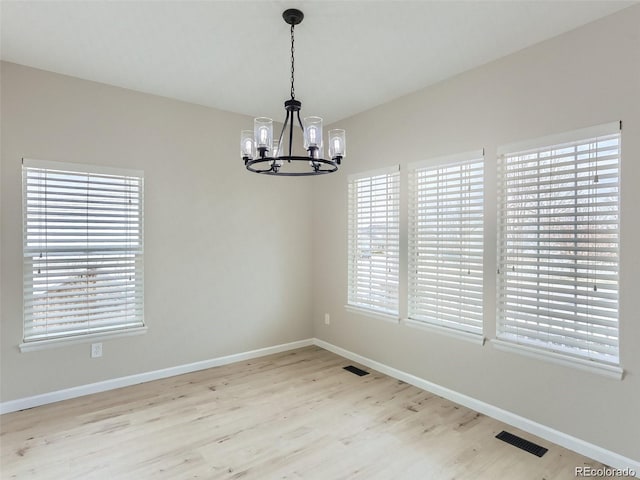 unfurnished dining area featuring a notable chandelier and light wood-type flooring