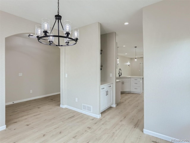 unfurnished dining area with a chandelier, sink, and light hardwood / wood-style floors