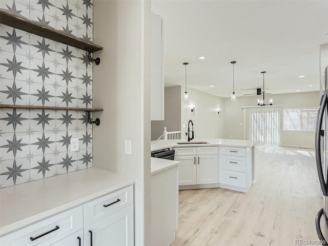 kitchen with white cabinetry, sink, hanging light fixtures, an inviting chandelier, and light hardwood / wood-style floors