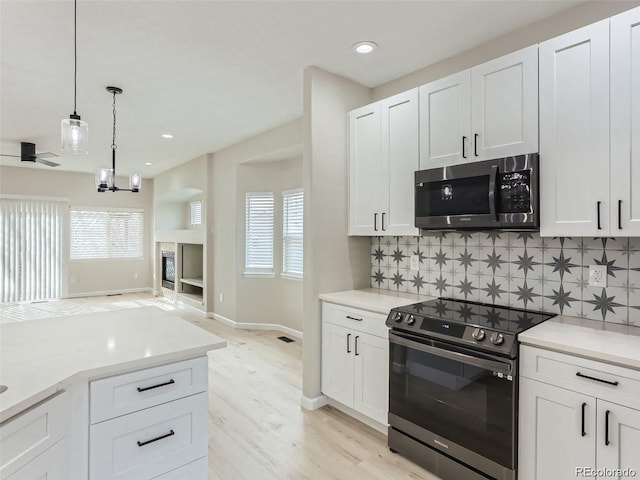 kitchen featuring white cabinetry, black range oven, light hardwood / wood-style flooring, decorative light fixtures, and decorative backsplash