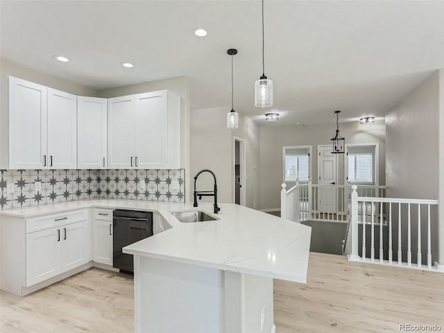 kitchen featuring kitchen peninsula, light stone countertops, sink, dishwasher, and white cabinets