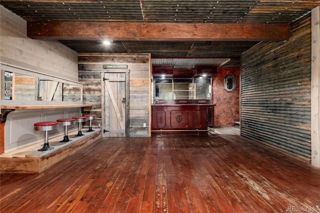 bar featuring hardwood / wood-style floors, wood walls, a barn door, and beam ceiling