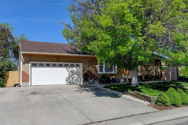 10769 Carrol Ln, Northglenn, CO 80233 - view of front of home featuring an attached garage, concrete driveway, fence, and brick siding