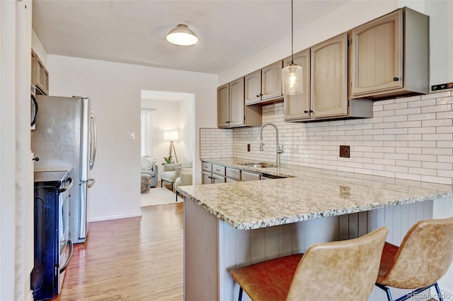 10769 Carrol Ln, Northglenn, CO 80233 - kitchen with stainless steel electric stove, a sink, light wood-style flooring, a peninsula, and backsplash