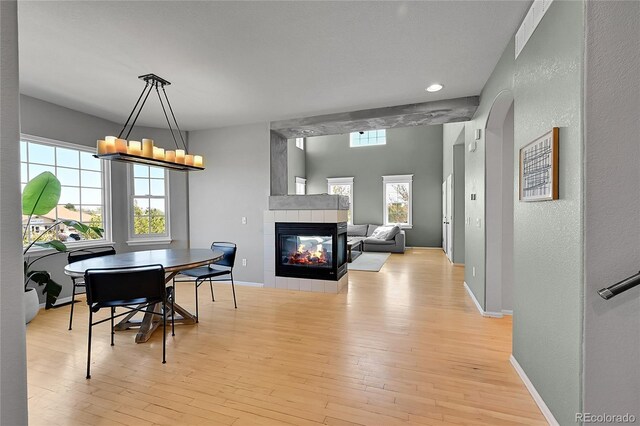 dining area featuring light wood finished floors, a textured wall, a tiled fireplace, baseboards, and recessed lighting