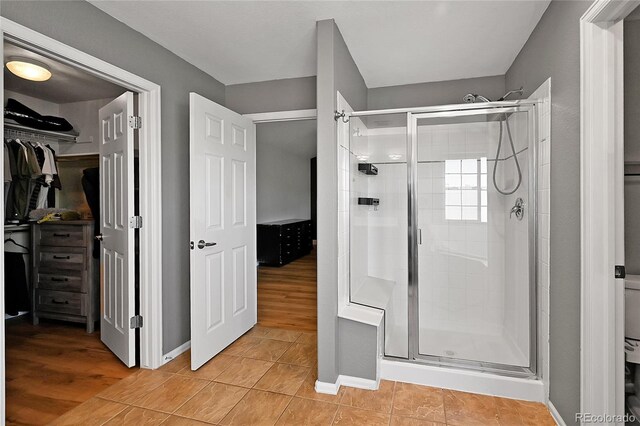bathroom with a shower stall, a spacious closet, baseboards, and tile patterned floors