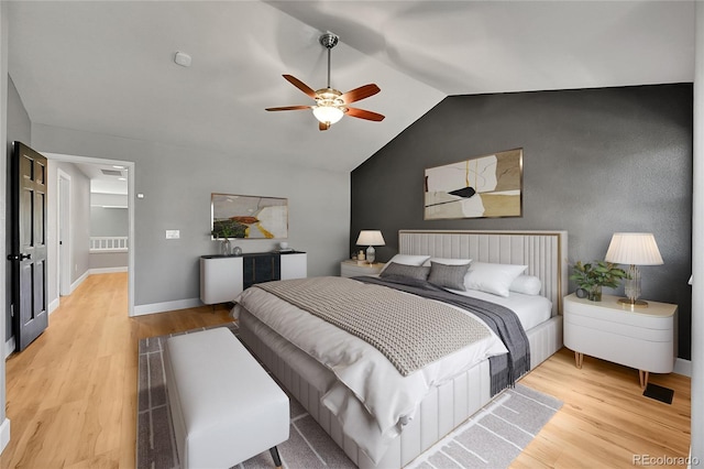 bedroom featuring light wood-style floors, lofted ceiling, baseboards, and ceiling fan
