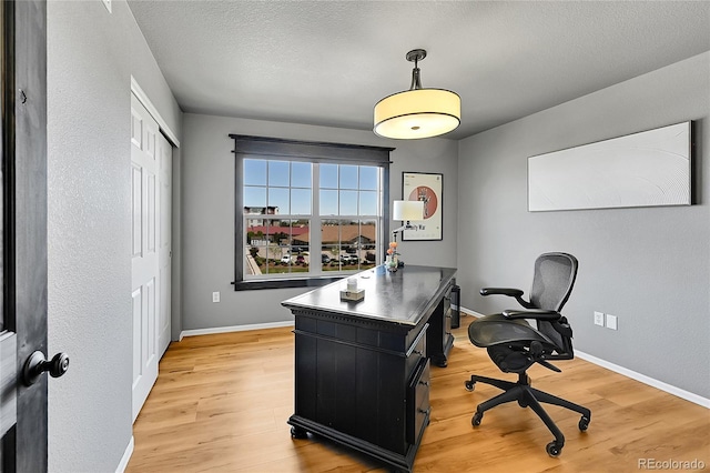 office featuring light wood finished floors, baseboards, and a textured ceiling
