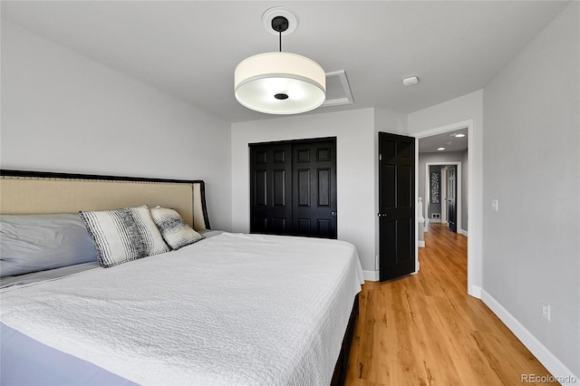 bedroom with light wood-style flooring, baseboards, and a closet