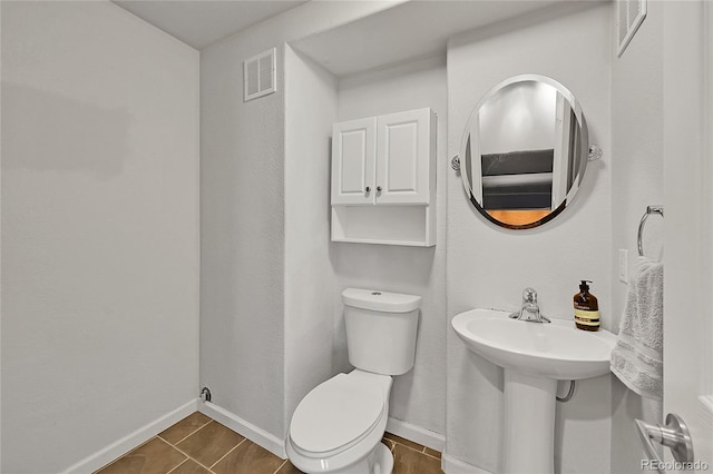 half bathroom with toilet, baseboards, and tile patterned floors