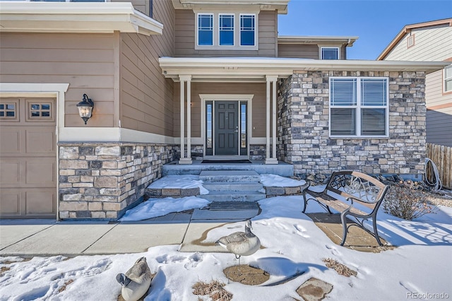 snow covered property entrance with a garage