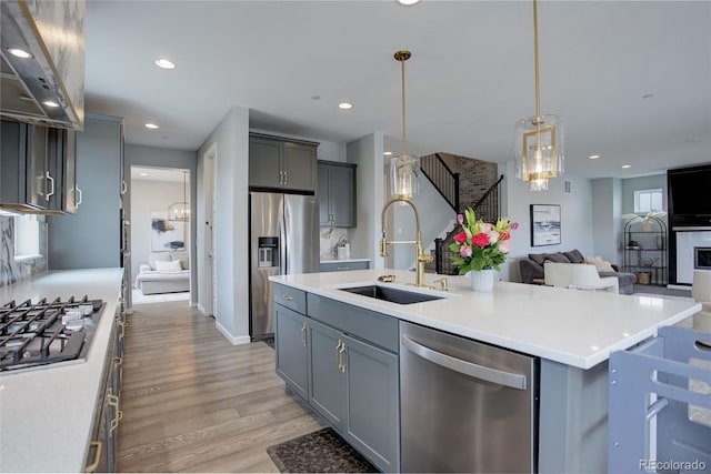 kitchen featuring a sink, appliances with stainless steel finishes, open floor plan, light wood-style floors, and extractor fan