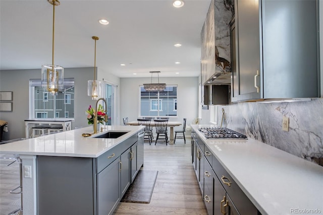 kitchen with backsplash, a sink, appliances with stainless steel finishes, gray cabinetry, and light wood-style flooring