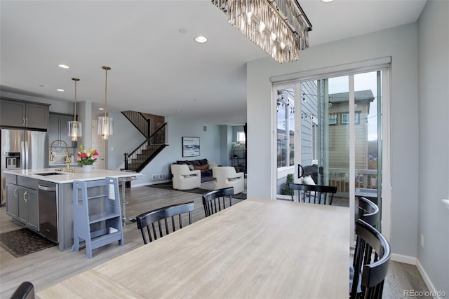 dining area with stairs, a notable chandelier, light wood-style flooring, baseboards, and recessed lighting