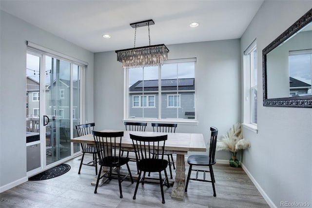 dining space with baseboards, wood finished floors, recessed lighting, and a notable chandelier