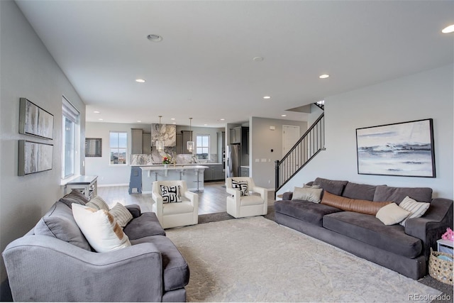 living room featuring baseboards, stairway, light wood-style floors, and recessed lighting