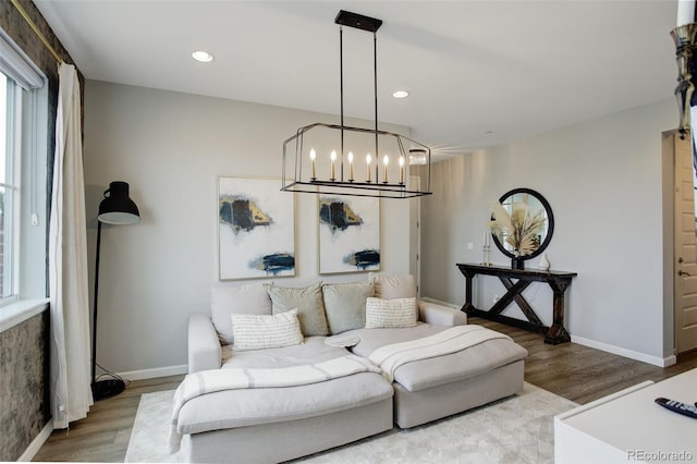 living area featuring baseboards, wood finished floors, recessed lighting, and a notable chandelier