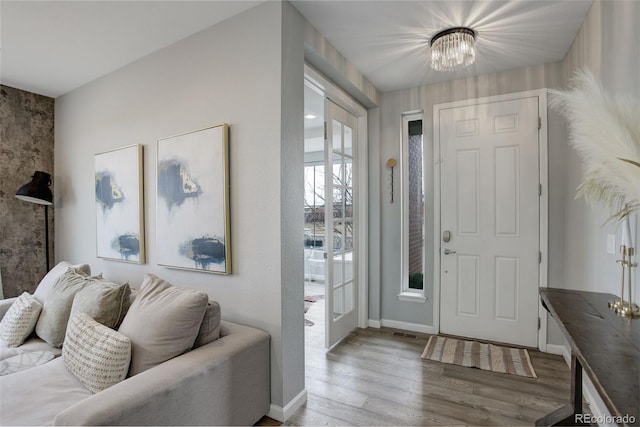 entrance foyer with baseboards, wood finished floors, and an inviting chandelier