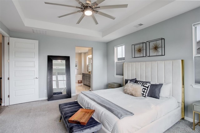 bedroom featuring carpet floors, a tray ceiling, baseboards, and visible vents
