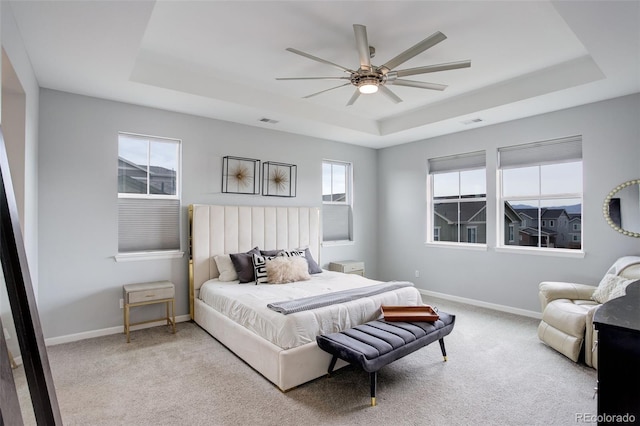 bedroom featuring a tray ceiling, baseboards, and carpet floors