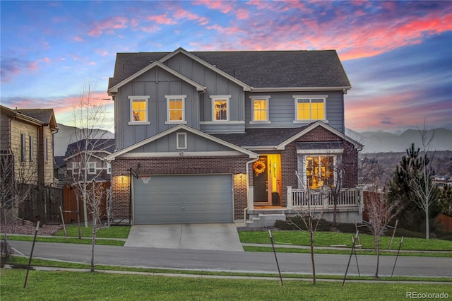 view of front of property with board and batten siding, driveway, an attached garage, and brick siding
