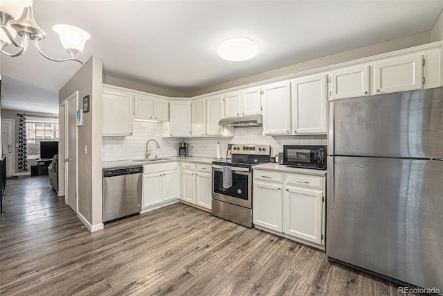 kitchen featuring stainless steel appliances, white cabinetry, a sink, and under cabinet range hood