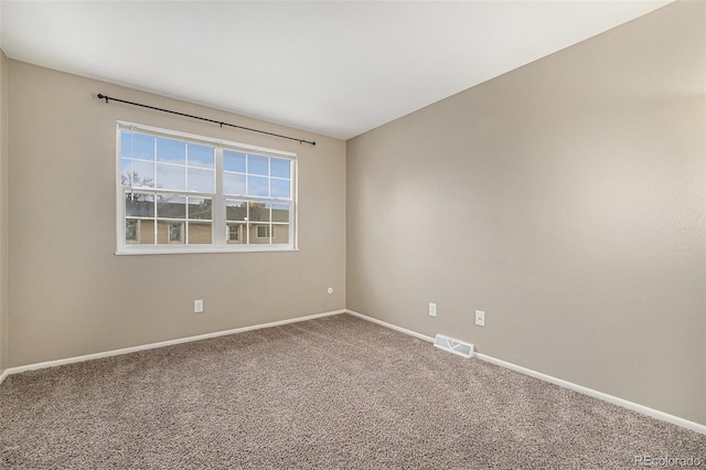 spare room with carpet, visible vents, and baseboards