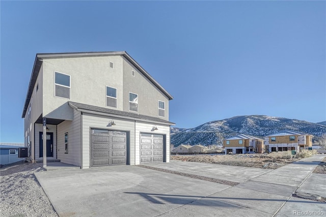 view of side of property featuring a mountain view, a garage, and central AC unit