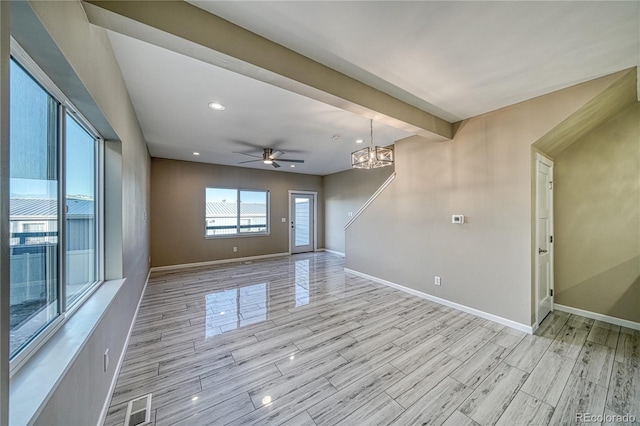 unfurnished living room with ceiling fan with notable chandelier and light hardwood / wood-style floors