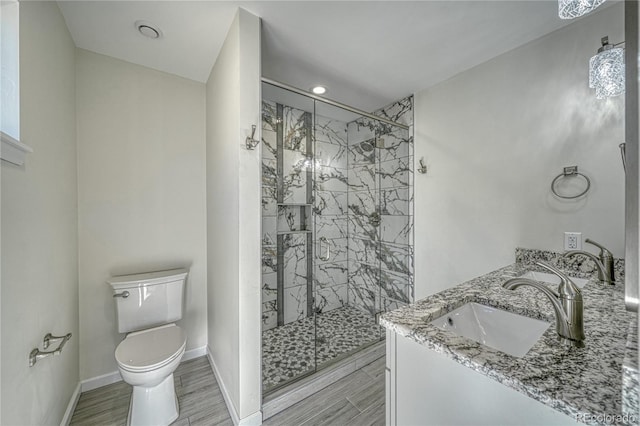 bathroom featuring wood-type flooring, vanity, toilet, and a shower with door