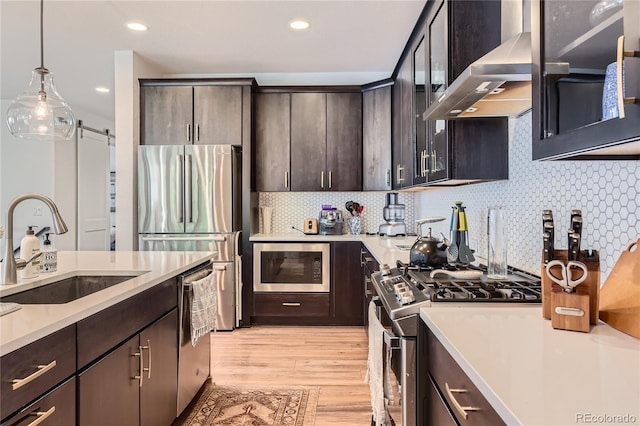 11253 Moondance Trl, Littleton, CO 80125 - kitchen featuring appliances with stainless steel finishes, a sink, wall chimney range hood, light countertops, and light wood finished floors