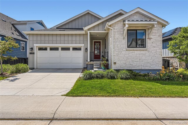 11253 Moondance Trl, Littleton, CO 80125 - view of front of property featuring board and batten siding, an attached garage, driveway, stone siding, and a front yard