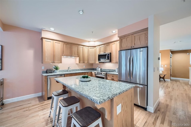 753 Pearl St, Boulder, CO 80302 - kitchen with appliances with stainless steel finishes, light wood-style flooring, a center island, a breakfast bar area, and baseboards