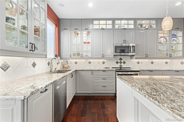 kitchen with gray cabinets, appliances with stainless steel finishes, sink, hanging light fixtures, and dark wood-type flooring