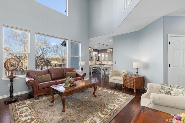 living room with dark wood-type flooring and a towering ceiling