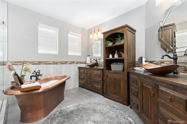 bathroom featuring a bath, vanity, and tile walls