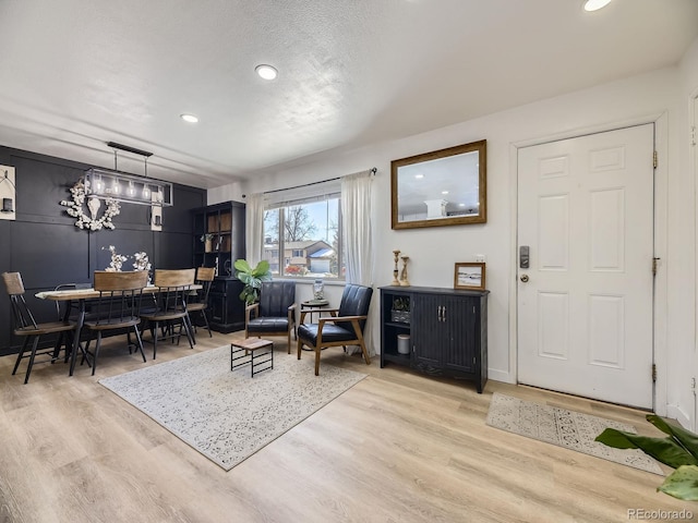 foyer entrance featuring a textured ceiling, light hardwood / wood-style floors, and a chandelier