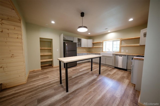 kitchen featuring black refrigerator, sink, stainless steel dishwasher, decorative light fixtures, and white cabinetry