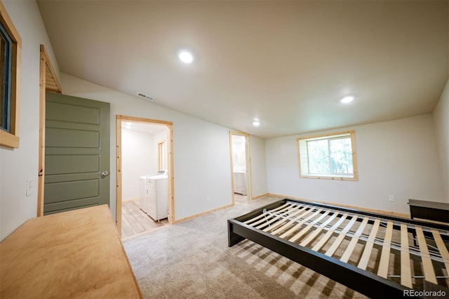 unfurnished bedroom featuring ensuite bathroom, light colored carpet, independent washer and dryer, and vaulted ceiling