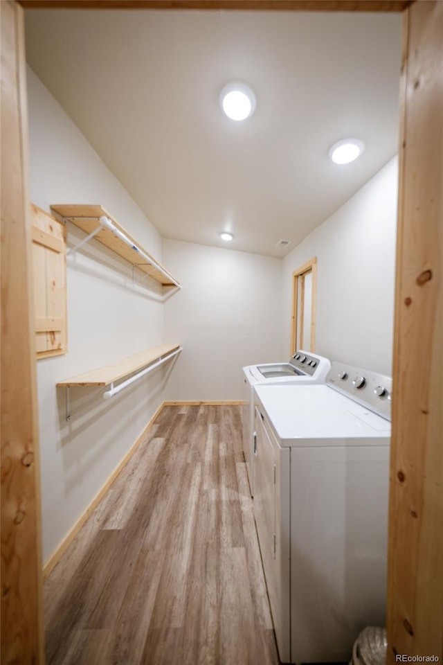 laundry area with independent washer and dryer and light hardwood / wood-style floors