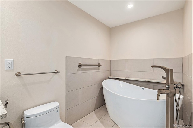 bathroom featuring tile walls, a tub to relax in, toilet, and tile patterned flooring